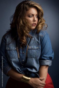 a woman is posing for a photo with her hands in her pockets and wearing a denim shirt