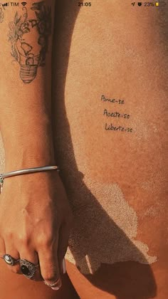 a woman's arm with tattoos on it and writing on the back of her body