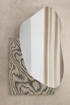 a mirror that is on the wall next to a wooden paneled surface with an abstract design