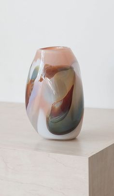 a glass vase sitting on top of a wooden table next to a white and brown wall