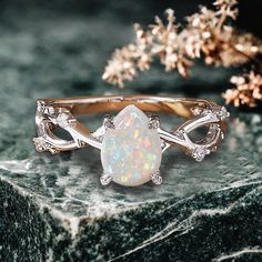 an opal and diamond ring sitting on top of a marble slab