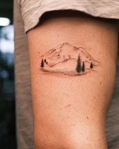 a person with a tattoo on their arm that has trees and mountains in the background