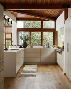 a kitchen with wooden ceiling and white cabinets in the center, along with an area rug on the floor