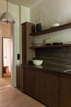 a kitchen with wooden cabinets and white bowls on the counter top, along with an open door leading to another room