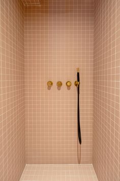 a tiled shower stall with two black and gold handles