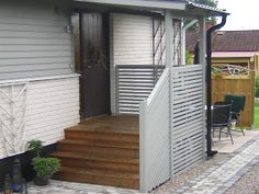 a small house with stairs leading up to the front door and patio area on either side