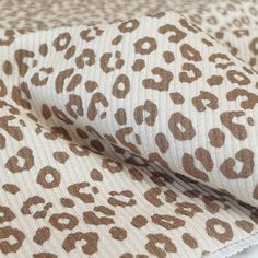 an animal print fabric with white and brown spots on the top, in various sizes