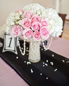 a vase filled with pink and white flowers sitting on top of a black table cloth