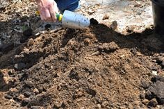 a person is digging in the dirt with a small metal tube on their left hand