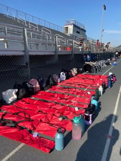 many bags are lined up on the side of the road with red tarp covering them