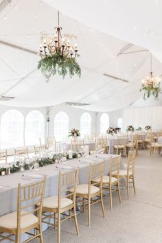 a large tent with tables and chairs set up for a formal dinner or reception in front of windows