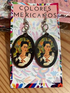 two earrings with the image of fridadors on them are sitting in front of a card