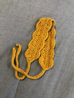 a yellow crocheted purse laying on top of a gray cloth