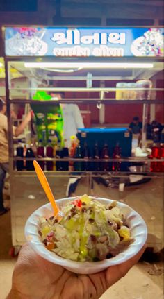 a person holding up a bowl of food in front of a store