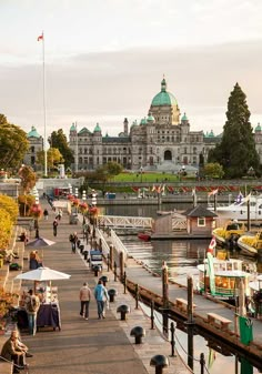 people are walking along the boardwalk in front of a large building