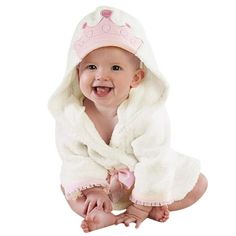 a smiling baby in a white robe and pink hat