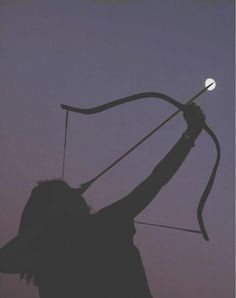 the silhouette of a person holding up a bow and arrow in front of a purple sky