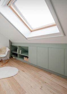 an attic bedroom with skylight and storage units in the corner, along with a white rug on the floor