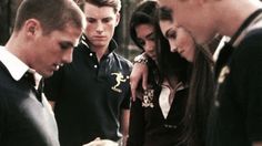 a group of young people standing around each other looking at something on a cell phone