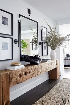 a wooden table topped with a mirror next to a vase filled with flowers and plants