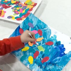 a young child is painting with colored paper