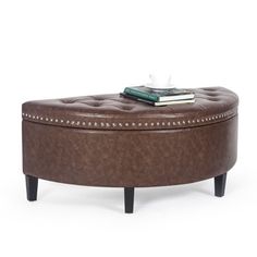 a brown ottoman sitting on top of a wooden table next to a book and cup