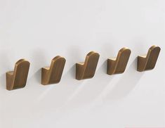 five brass - plated hooks are lined up against the wall, one has a curved handle