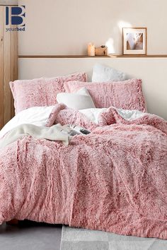 a bed with pink comforter and pillows in a bedroom