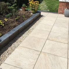 an outdoor patio area with stone steps and flowers in the foreground, surrounded by grass