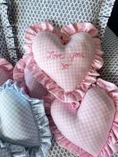 two heart shaped pillows with the words love you so written on them sitting next to each other