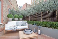 an outdoor living area with white furniture and potted plants on the side of the building