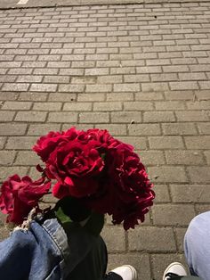 two people sitting on the sidewalk with flowers in their lap