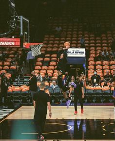 the basketball players are playing on the court in front of an audience with orange seats