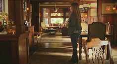 a woman standing in a living room next to a table