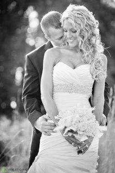 a bride and groom standing together in the grass