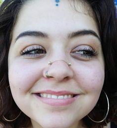 a close up of a woman with piercings on her nose and wearing large hoop earrings