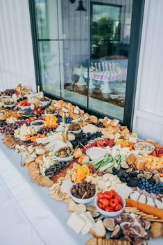 a long table filled with lots of different types of food on top of a white table cloth