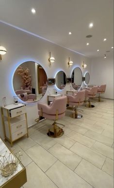 a room filled with lots of pink chairs and mirrors in front of round mirrors on the wall