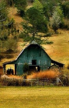 an old barn sits in the middle of a field