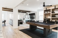 a pool table in the middle of a living room with built - in shelving