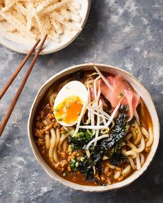 a bowl of ramen with an egg on top and chopsticks next to it