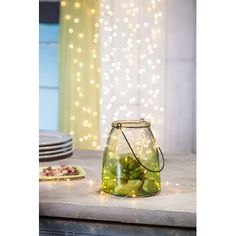 a glass jar filled with pickles sitting on top of a counter next to plates