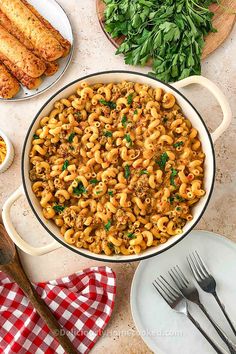 a large pot filled with pasta next to some bread and other food on the table