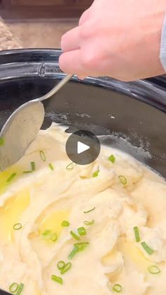 a person is spooning mashed potatoes into a crock pot with green onions