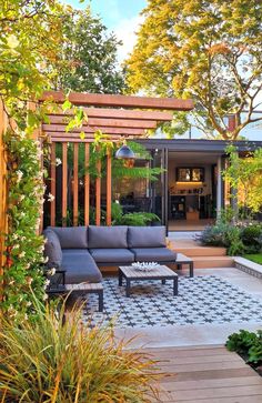 an outdoor living area with couches and tables in the foreground, surrounded by greenery