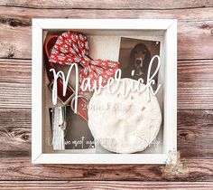 a white frame with red and white items in it on a wooden table next to a brown dog