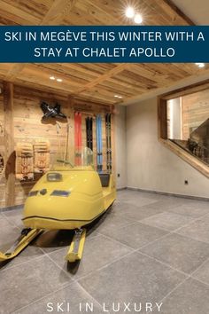 there is a yellow snowmobile in the middle of a room with stairs and windows