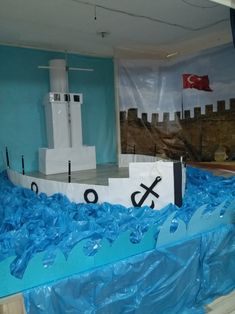 a boat made out of plastic sitting on top of a blue tarp in front of a flag