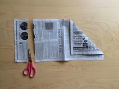 a pair of pink scissors sitting on top of a piece of newspaper next to a pair of glasses