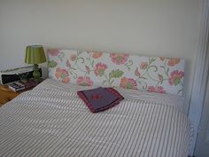 a bed with a striped comforter on top of it and a lamp next to it